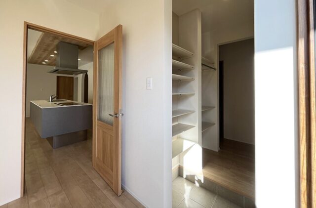 白の外壁に木目が映える豊かな緑と調和した光あふれる平屋 - 向洋ハウジング - 玄関・LDK