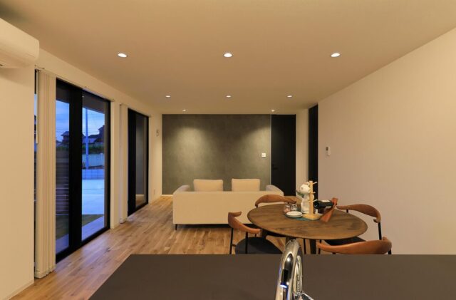 昼と夜で表情を変える外観のモノトーン×木の平屋 - 森建築 - 夜・LDK